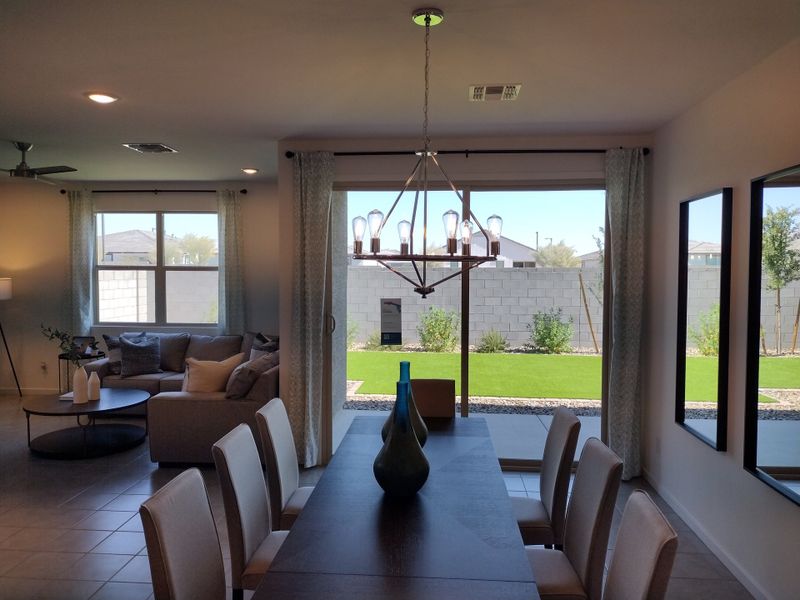 A modern dining area with elegant lighting, large windows, and a view of a landscaped backyard in a contemporary home. A modern dining area with elegant lighting, large windows, and a view of a landscaped backyard in a contemporary home.