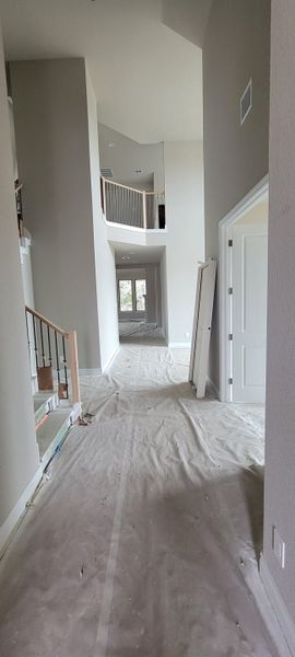 A grand foyer under construction with high ceilings, bright white walls, and elegant staircase railing.