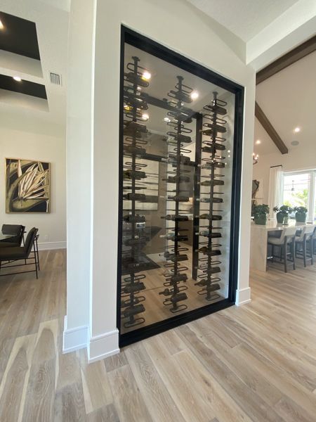 A sleek, modern wine display with glass doors and elegant black metal racks on a light wood floor.