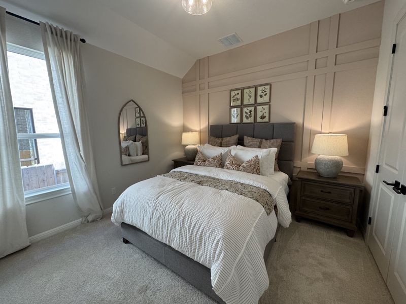 A cozy bedroom with a tufted headboard, elegant paneling, and soft lighting, complemented by a stylish mirror and curtains.