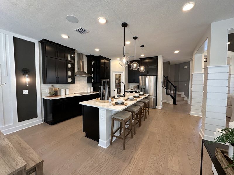 A modern kitchen with dark cabinets, pendant lighting, and a large island with seating. A modern kitchen with dark cabinets, pendant lighting, and a large island with seating.