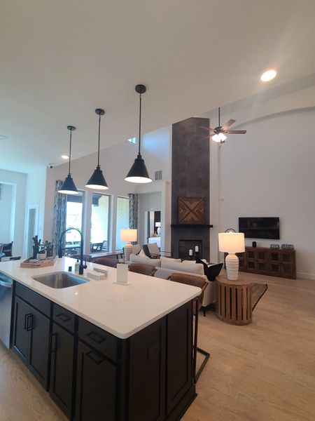 A spacious living area with high ceilings, sleek island kitchen, cozy seating, and modern lighting.