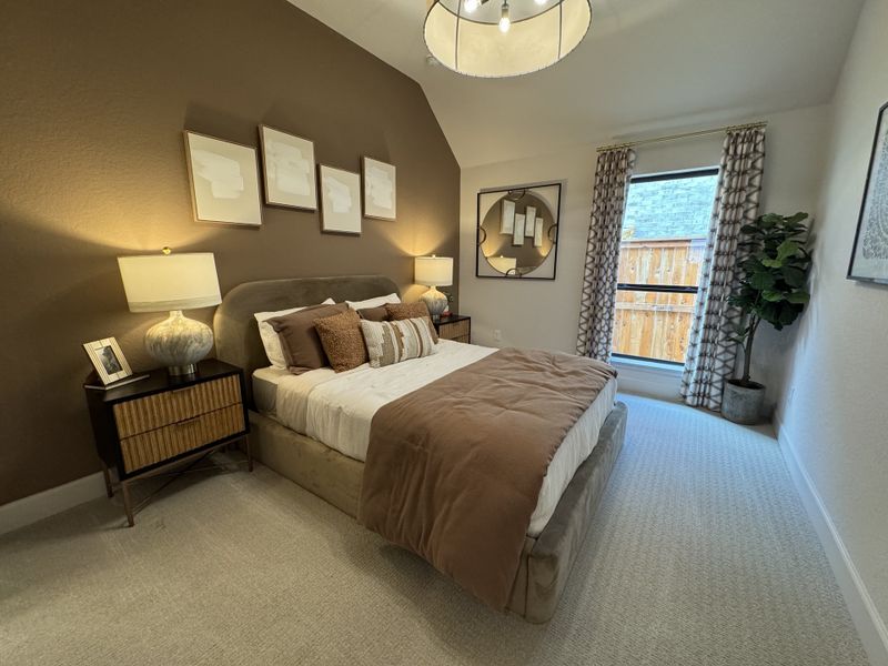 A cozy bedroom with a plush bed, elegant lighting, and neutral tones, featuring chic wall art and a large window.