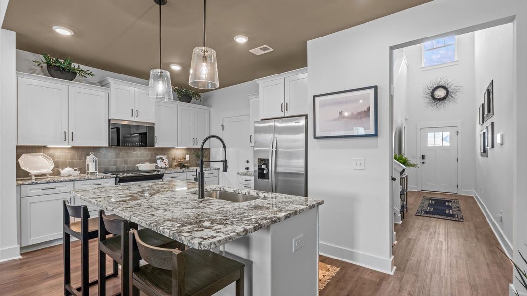 Superior kitchen with quartz countertops, pendant lighting, and a generously sized island at the new Robert's Farm community