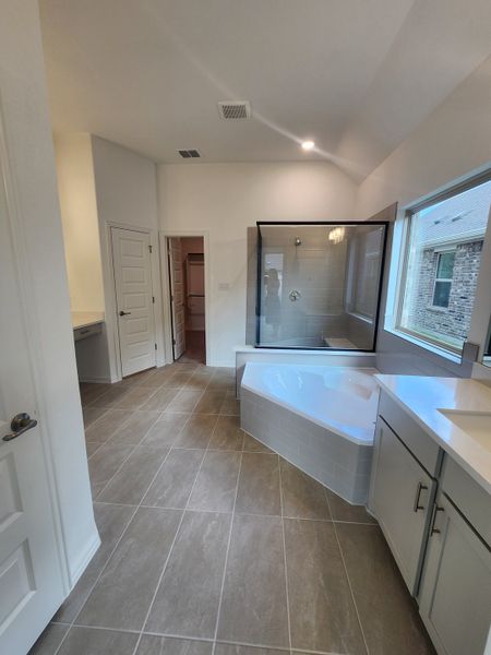 A spacious bathroom featuring a corner tub, glass shower, and sleek cabinetry with large tiles. A spacious bathroom featuring a corner tub, glass shower, and sleek cabinetry with large tiles.