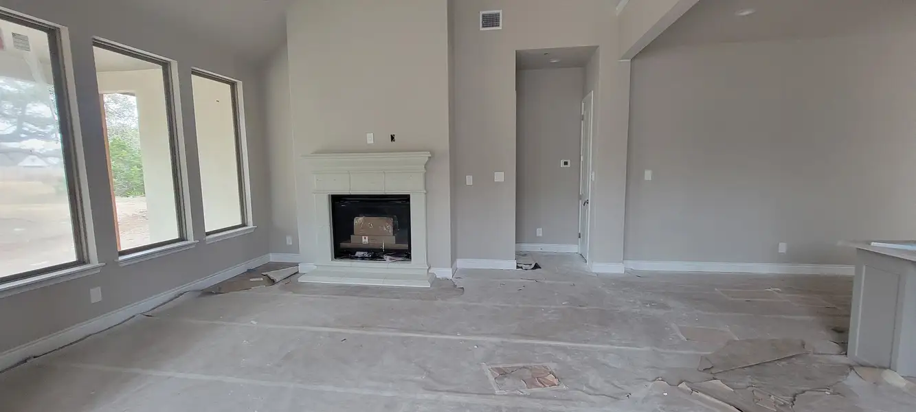 An unfinished living room with large windows and a white fireplace, ready for customization. An unfinished living room with large windows and a white fireplace, ready for customization.