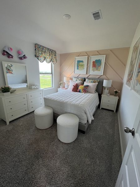 A cozy bedroom featuring a white bed, colorful pillows, plush carpet, and vibrant wall art. A cozy bedroom featuring a white bed, colorful pillows, plush carpet, and vibrant wall art.