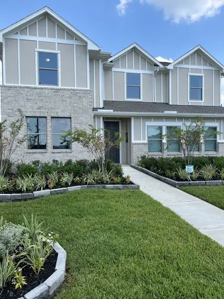 A charming gray and white home with lush landscaping in Windcress by Coventry Homes (Cove, TX).