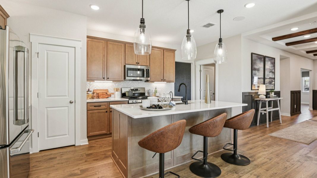 The kitchen features 42 inch wood cabinetry with industrial style pendant lighting above the center island The kitchen features 42 inch wood cabinetry with industrial style pendant lighting above the center island