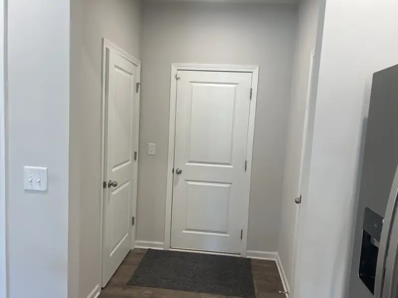 A modern hallway featuring crisp white doors, sleek gray walls, and elegant wooden flooring. A modern hallway featuring crisp white doors, sleek gray walls, and elegant wooden flooring.