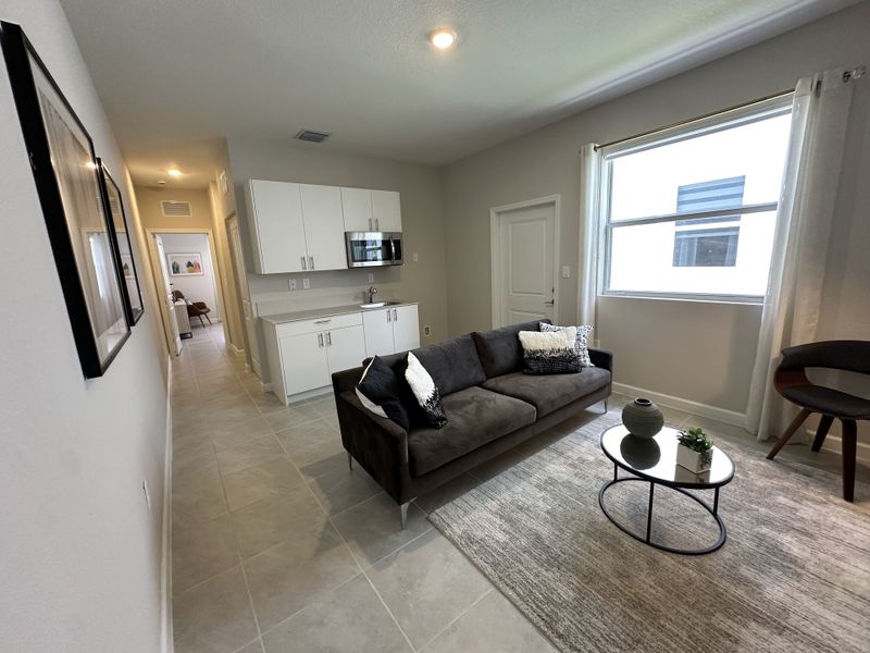 A cozy living area featuring a sleek gray sofa, minimalist decor, and a bright window with natural light enhancing the neutral palette.