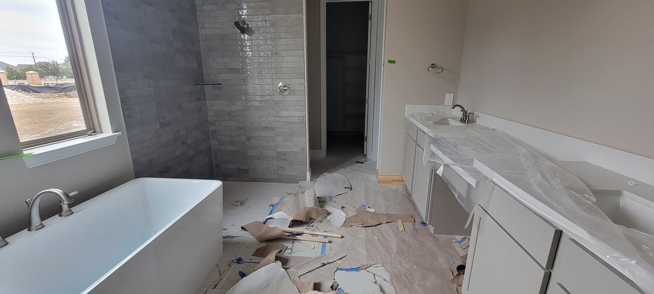 A modern bathroom under construction with a sleek soaking tub, spacious shower, and double sink vanity.