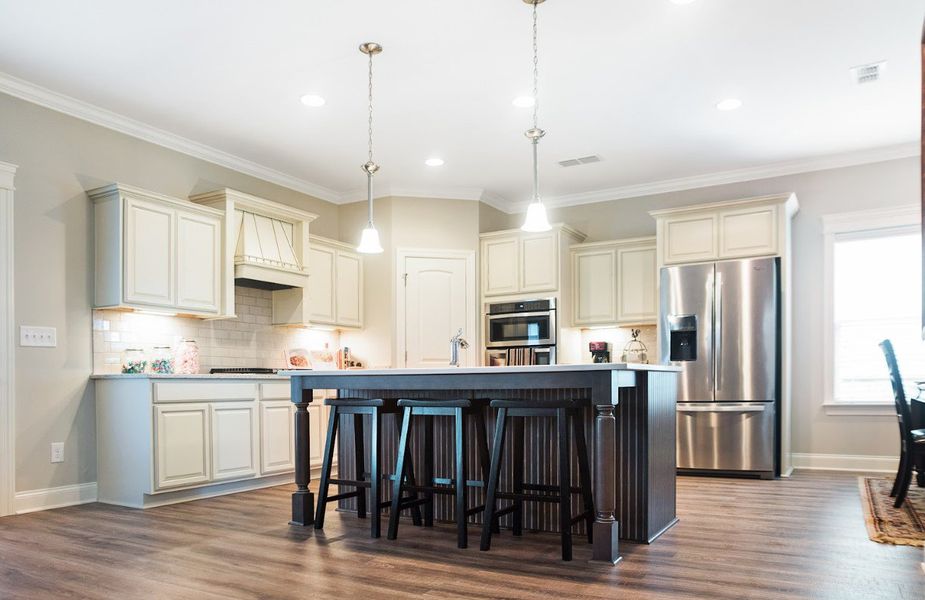 Elegant and functional, this kitchen features soft cream cabinetry, a spacious island with seating, high-end stainless steel appliances, quartz countertops, and warm wood flooring Elegant and functional, this kitchen features soft cream cabinetry, a spacious island with seating, high-end stainless steel appliances, quartz countertops, and warm wood flooring