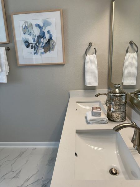 Elegant bathroom featuring a sleek sink, modern faucet, artful wall decor, and luxurious marble floor tiles.
