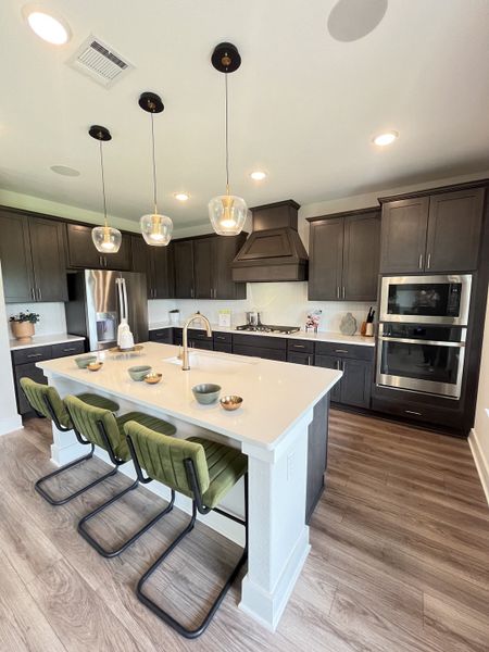 A modern kitchen with sleek dark cabinets, an elegant island, and stylish pendant lighting.