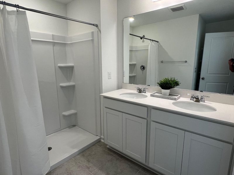 A sleek bathroom with a spacious shower, dual sinks, a large mirror, and minimalistic decor for a clean, modern feel.