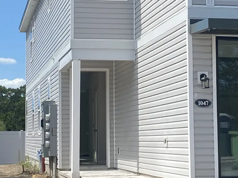 A modern gray siding home featuring a quaint porch in Egret Creek by Mattamy Homes (Jacksonville, FL).