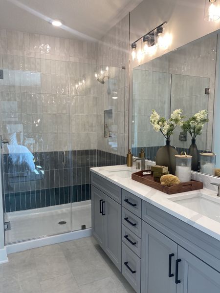 Elegant bathroom with a glass shower, soft gray vanity, sleek lighting, and stylish decor accents. Elegant bathroom with a glass shower, soft gray vanity, sleek lighting, and stylish decor accents.