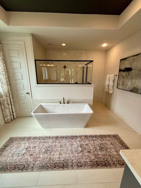 A serene bathroom with a sleek freestanding tub, elegant tiling, and a chic patterned rug for a modern touch.