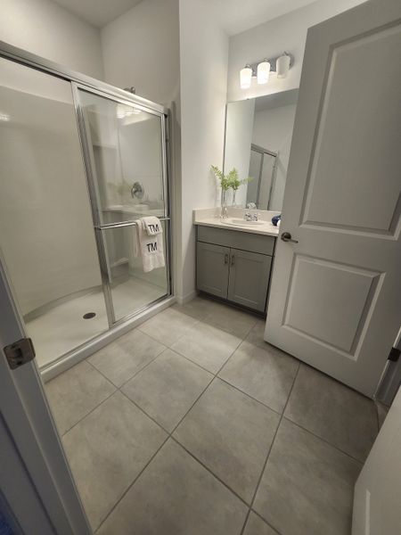 A modern bathroom featuring a sleek shower, elegant vanity, and bright lighting.