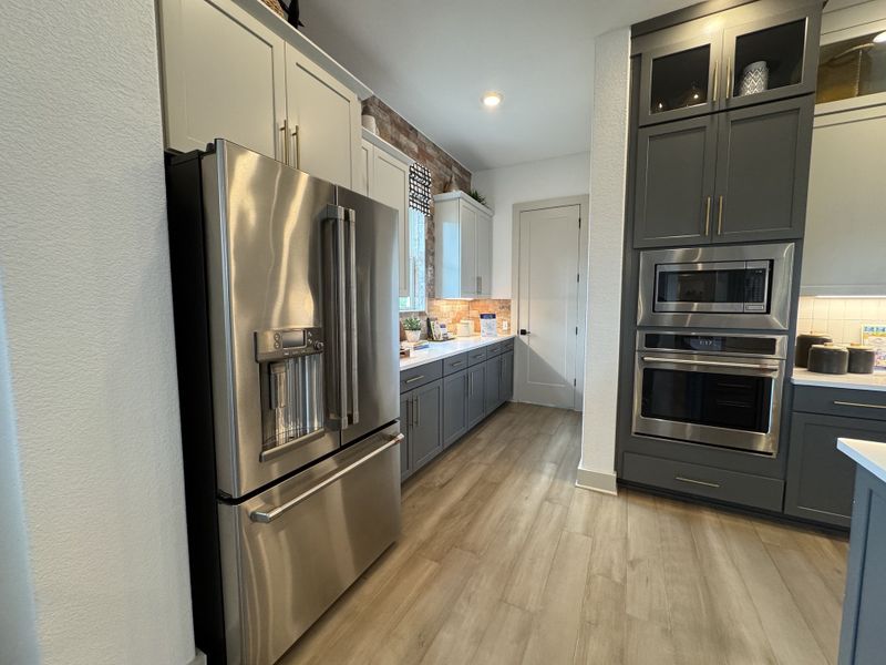A modern kitchen with sleek stainless steel appliances, elegant cabinetry, and warm wood floors.