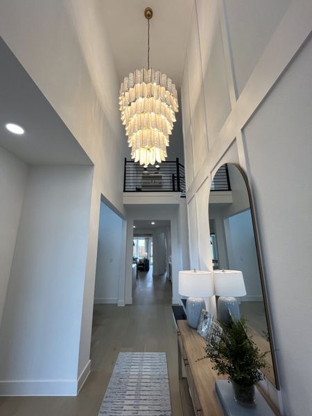A modern hallway with a statement chandelier, tall ceilings, and elegant decor. A modern hallway with a statement chandelier, tall ceilings, and elegant decor.