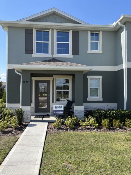 A charming townhome exterior with a covered entry, lush landscaping, and contemporary design in Avian Pointe Townhomes by D.R. Horton (Apopka, FL).