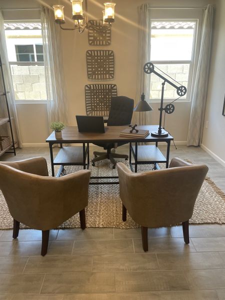 A cozy home office with modern decor, featuring a stylish desk, two comfortable chairs, and a chic chandelier.