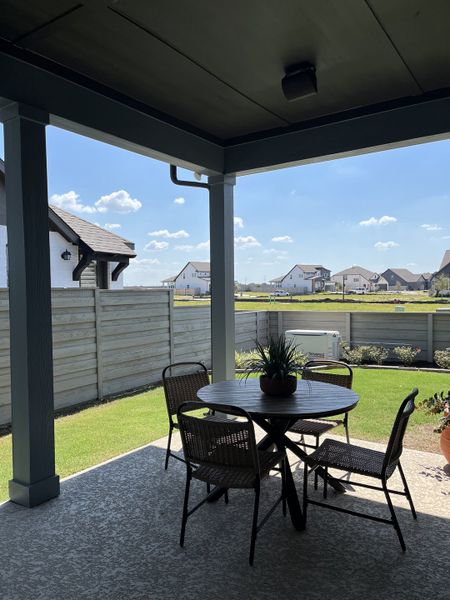 A cozy covered patio with wicker furniture and a view of a sunny yard, perfect for outdoor relaxation. A cozy covered patio with wicker furniture and a view of a sunny yard, perfect for outdoor relaxation.