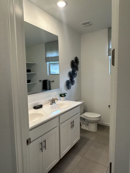 A well-appointed guest bathroom with dual sinks, white cabinetry, and modern decor.