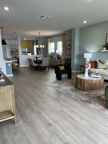 A spacious, modern living area with soft tones, wooden flooring, and elegant furnishings.