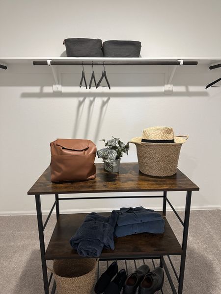 A neatly organized closet with wooden shelves, baskets, a hat, and neatly folded clothes. A neatly organized closet with wooden shelves, baskets, a hat, and neatly folded clothes.