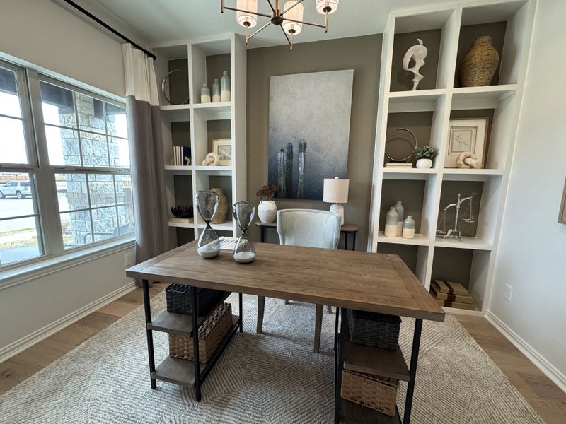 A chic home office with built-in shelves, a wooden desk, large window, and stylish decor. A chic home office with built-in shelves, a wooden desk, large window, and stylish decor.