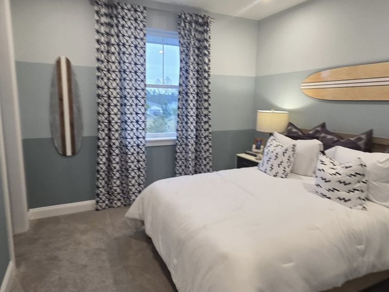 A cozy bedroom featuring nautical decor, patterned curtains, and a surfboard wall accent, creating a serene atmosphere. A cozy bedroom featuring nautical decor, patterned curtains, and a surfboard wall accent, creating a serene atmosphere.