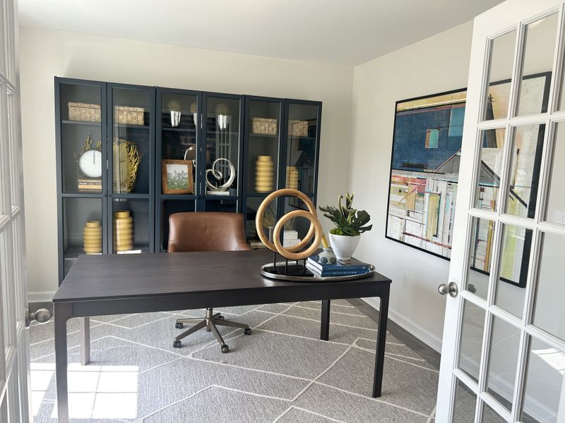 A modern office with a sleek desk, leather chair, stylish bookshelf, and abstract wall art for a productive work environment.