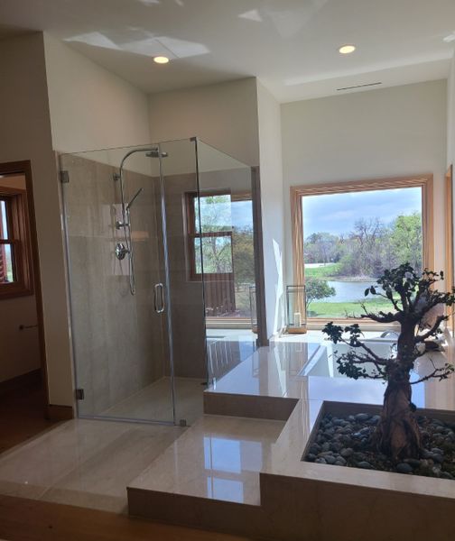 A sophisticated bathroom with a glass shower, large window views, and a stylish indoor bonsai feature. A sophisticated bathroom with a glass shower, large window views, and a stylish indoor bonsai feature.