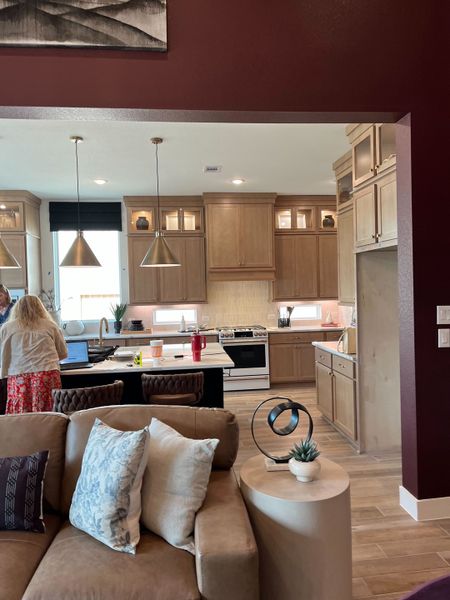 A modern kitchen with light wood cabinets, pendant lighting, and a cozy seating area, blending style and functionality.