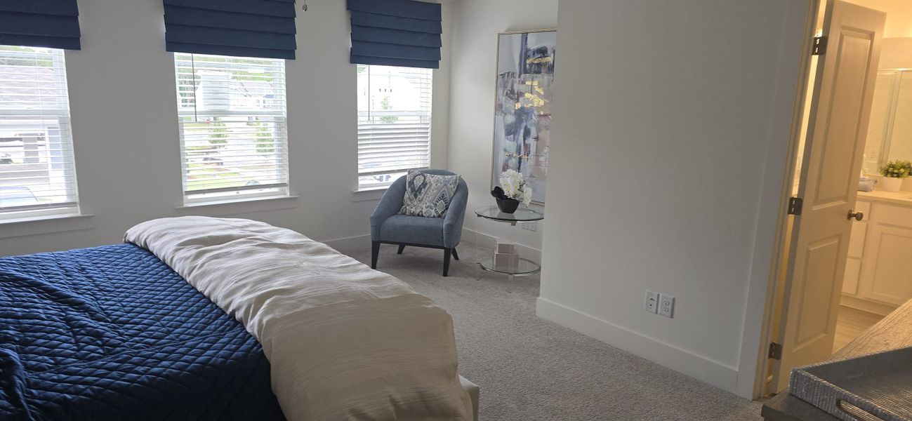 A cozy bedroom with a plush blue chair, abstract art, and a serene ambiance.