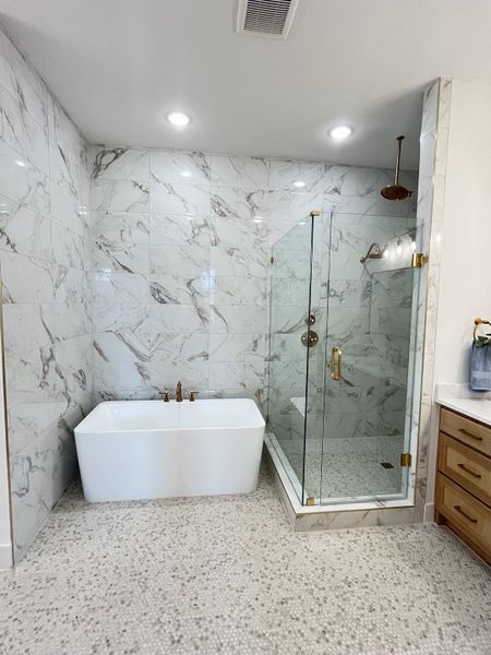 A luxurious bathroom with a marble-tiled shower, freestanding tub, and elegant fixtures. A luxurious bathroom with a marble-tiled shower, freestanding tub, and elegant fixtures.