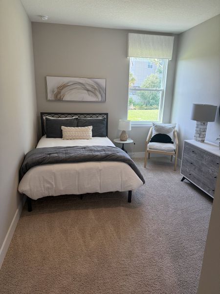 A cozy bedroom with neutral tones, a single bed, modern art, and a bright window view. A cozy bedroom with neutral tones, a single bed, modern art, and a bright window view.