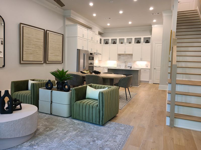 A modern living space with olive green seating, stylish decor, and sleek cabinetry leading to a staircase. A modern living space with olive green seating, stylish decor, and sleek cabinetry leading to a staircase.