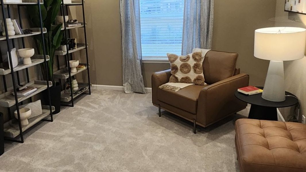 A stylish lounge with open shelving, accent seating, and natural lighting, perfect for relaxation or reading.