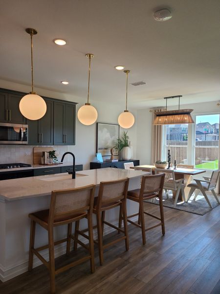 A modern kitchen with sleek black cabinetry, pendant lighting, and a spacious island with wooden bar stools. A modern kitchen with sleek black cabinetry, pendant lighting, and a spacious island with wooden bar stools.
