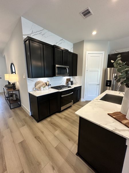 Modern kitchen with sleek black cabinetry, marble counters, and wood flooring for a stylish and functional space.