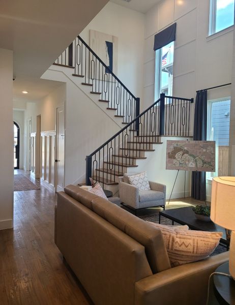 A modern living area with elegant staircase, cozy seating, and abundant natural light.