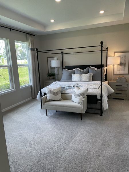 A cozy bedroom with a modern canopy bed, soft gray carpet, and elegant lighting, offering a serene retreat. A cozy bedroom with a modern canopy bed, soft gray carpet, and elegant lighting, offering a serene retreat.