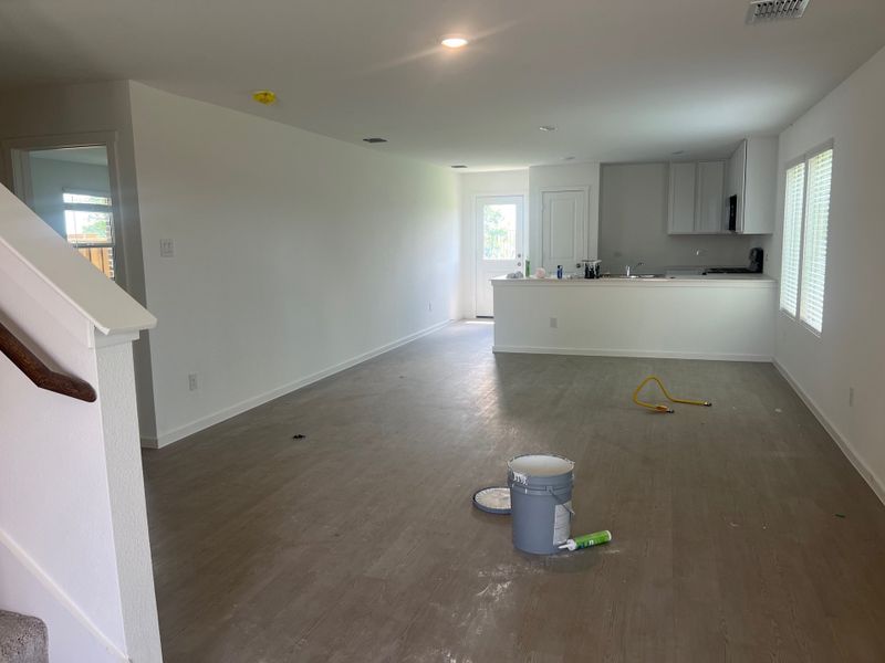 A spacious, unfinished living room with light wood flooring and an open kitchen, ready for personalization. A spacious, unfinished living room with light wood flooring and an open kitchen, ready for personalization.