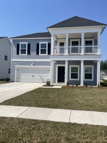 A charming two-story home with a balcony and manicured lawn in Sweetgrass at Summers Corner by Lennar (Ridgeville, SC).
