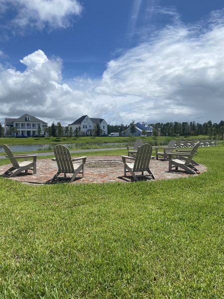 Charming outdoor space with Adirondack chairs in Seven Pines by ICI Homes, offering lush green lawns in Jacksonville, FL.