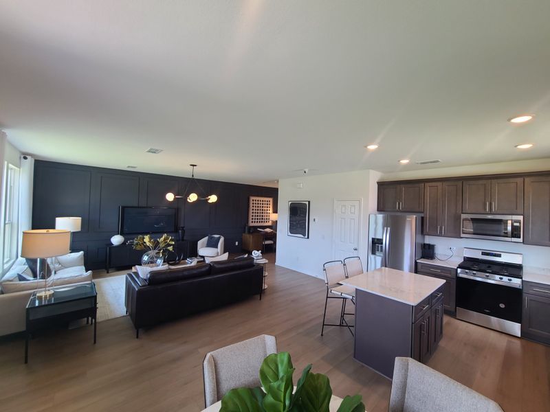 Modern open-plan living area with sleek kitchen, dark accent wall, and contemporary furnishings. Bright and inviting space. Modern open-plan living area with sleek kitchen, dark accent wall, and contemporary furnishings. Bright and inviting space.